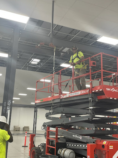 A man standing on top of a scissor in a warehouse